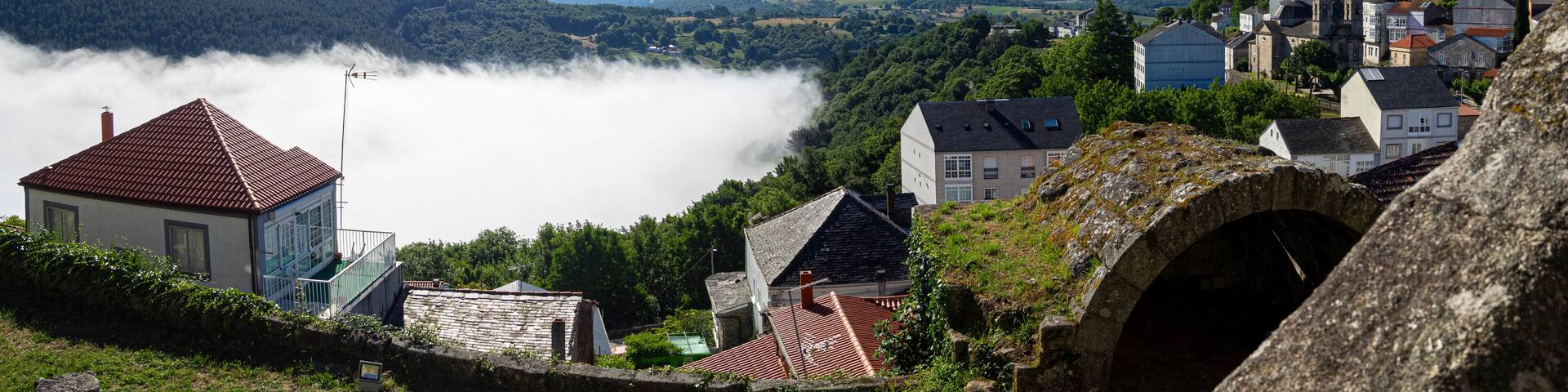 Vista panorámica de un mar de nubes blancas sobre los tejados, desde el Castillo del pueblo bonito de España, Castro Caldelas, en Orense, verano de 2021