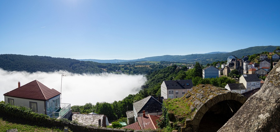 Vista panorámica de un mar de nubes blancas sobre los tejados, desde el Castillo del pueblo bonito de España, Castro Caldelas, en Orense, verano de 2021