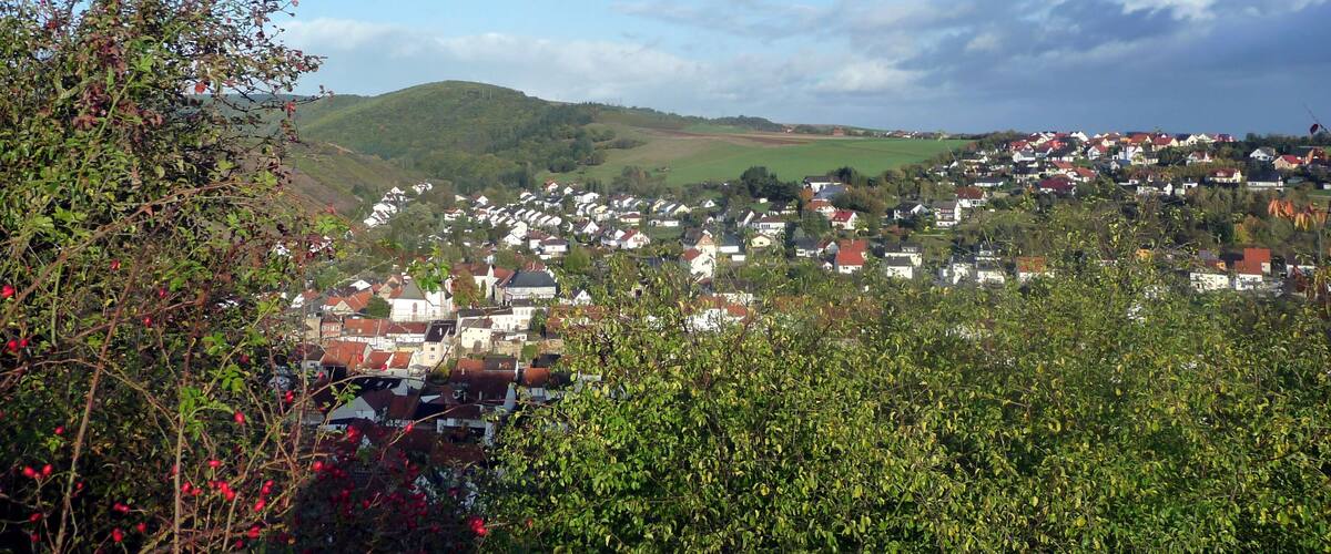 A village nestled in a valley with green hills in the background.