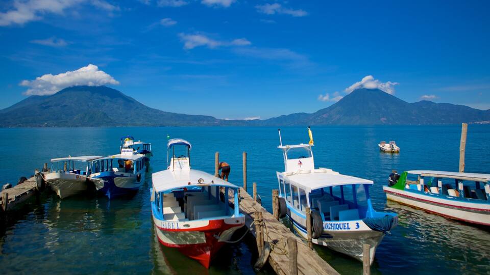 A marina with several boats docked, a mountainous landscape in the background, and clear blue skies.