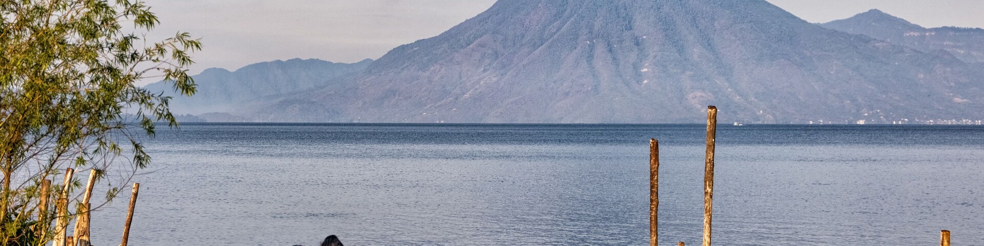 Un grupo de personas junto a un lago, con una montaña al fondo.