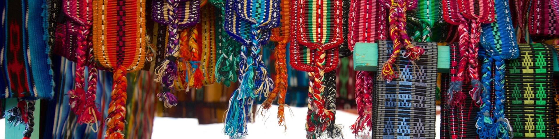 A market stall with colorful woven textiles and a pair of shoes.