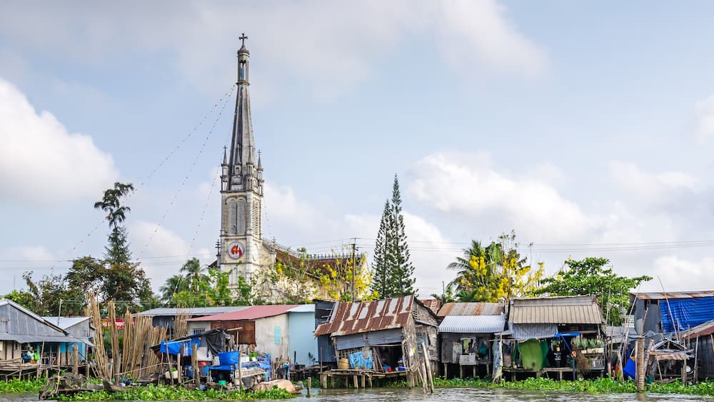 One of the banks of the Mekong river with the Cathedral of Cai Be, a river-land mixed town in Vietnam