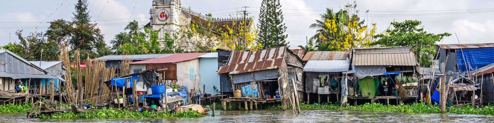 One of the banks of the Mekong river with the Cathedral of Cai Be, a river-land mixed town in Vietnam