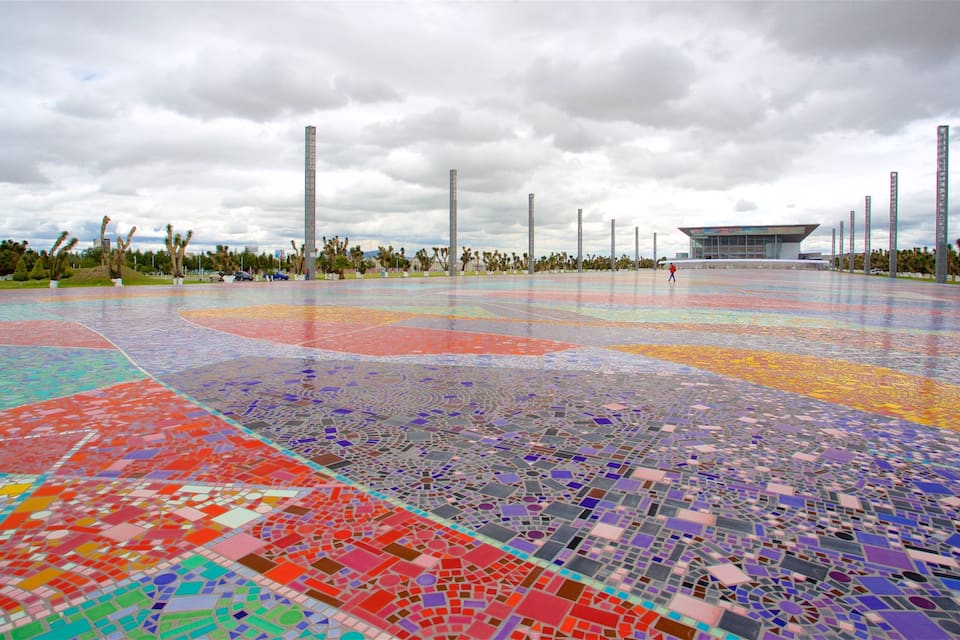 Une place pavée de mosaïques, avec un bâtiment moderne en arrière-plan.