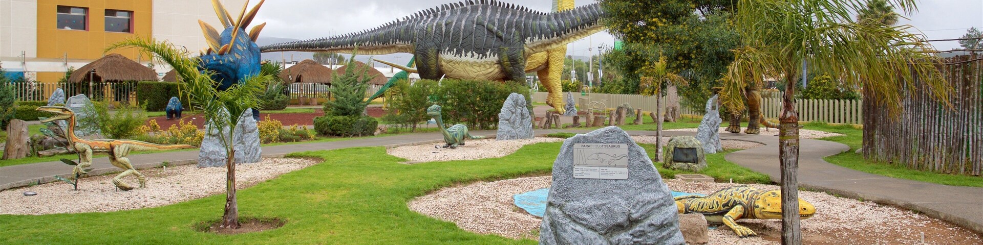 A dinosaur-themed park with various dinosaur sculptures and a large dinosaur model.