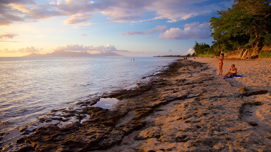 Society Islands showing rocky coastline, a beach and a sunset
