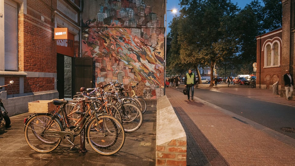 Varias bicicletas estacionadas junto a una pared con un mural colorido.