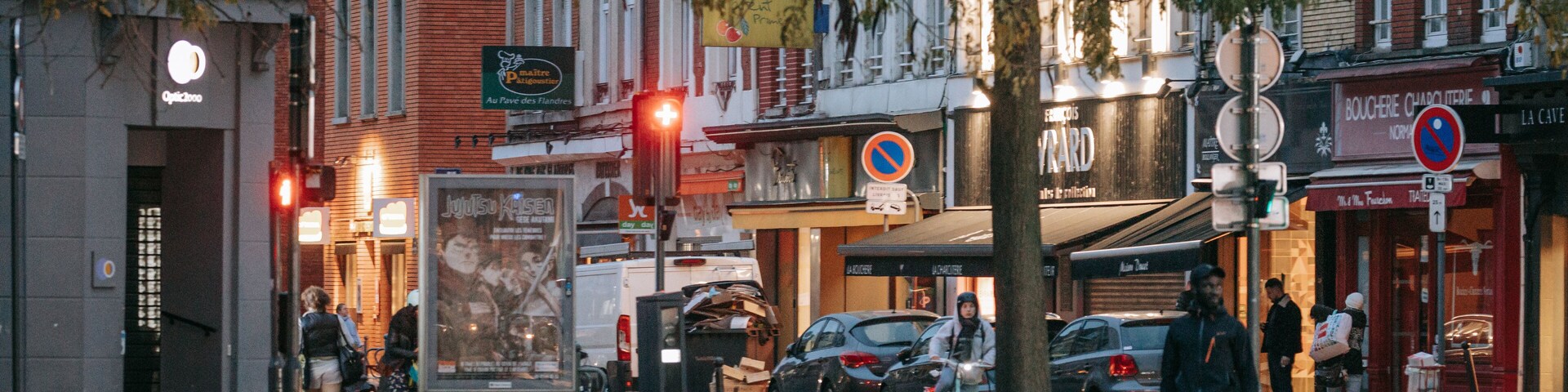 Una calle urbana con edificios, una señal de no estacionamiento y una parada de autobús.