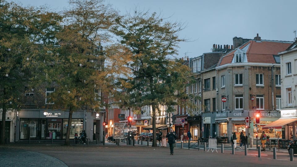 Una calle de ciudad europea con edificios históricos, tiendas y un café.