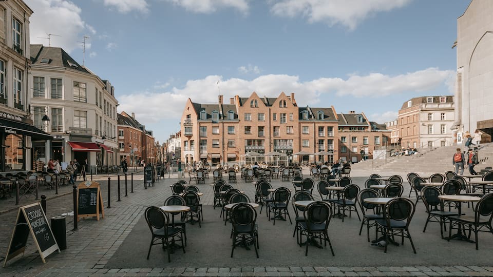 Une place pavée, avec des terrasses et des bâtiments historiques.