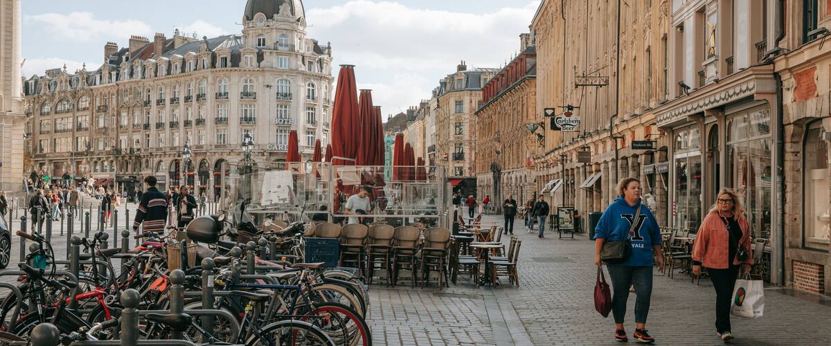 A cobblestone street with historic buildings, a dome structure, and a café with outdoor seating.