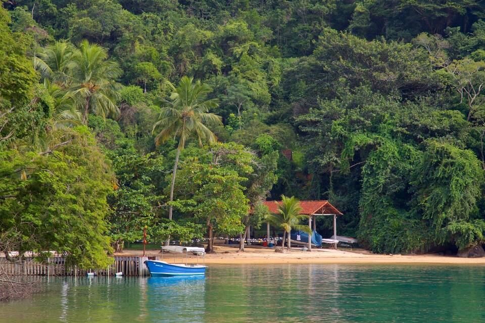 Uma praia com uma cabana pequena e um barco azul.