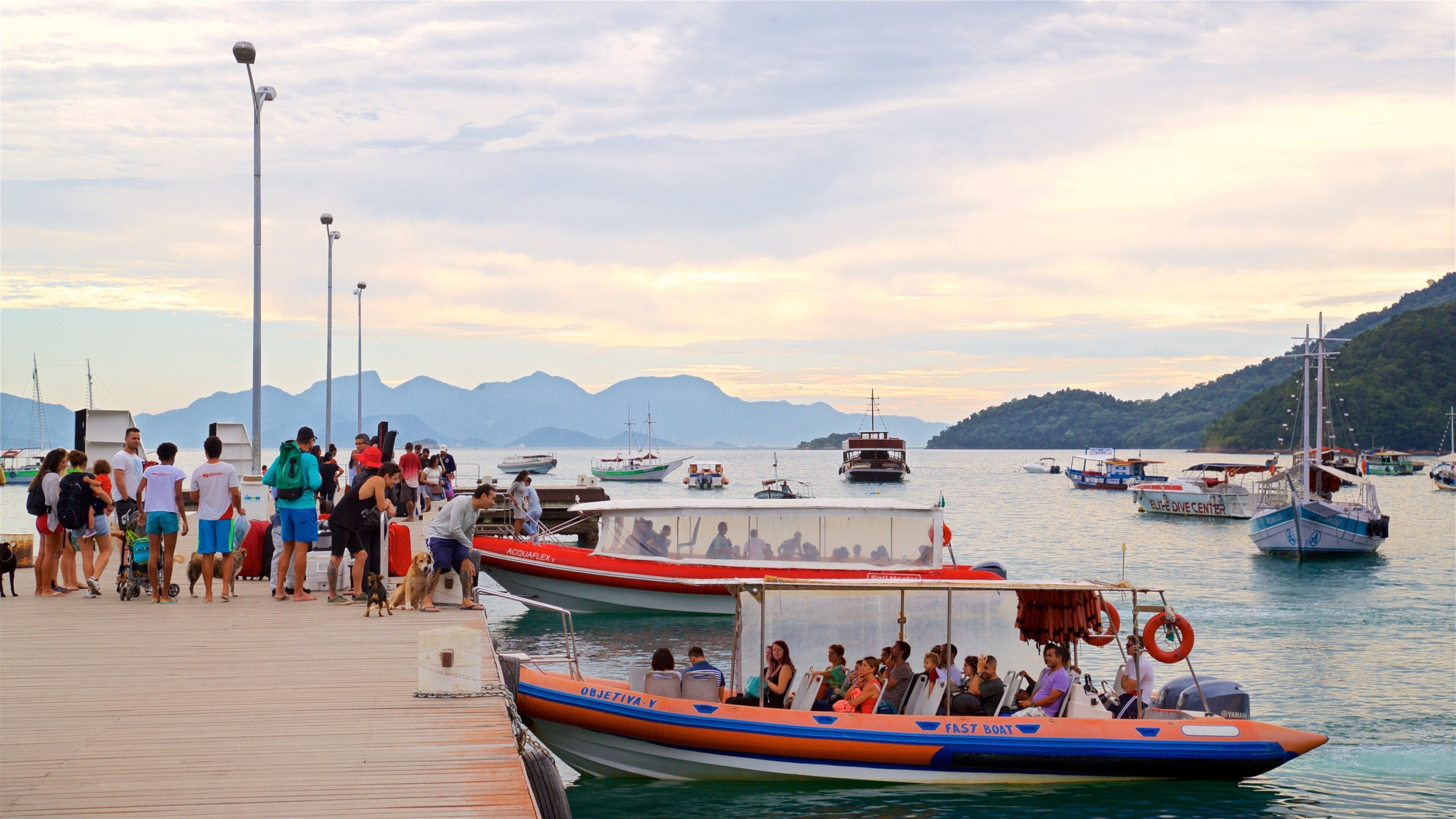 Abraao Beach which includes a sunset and a bay or harbor as well as a small group of people