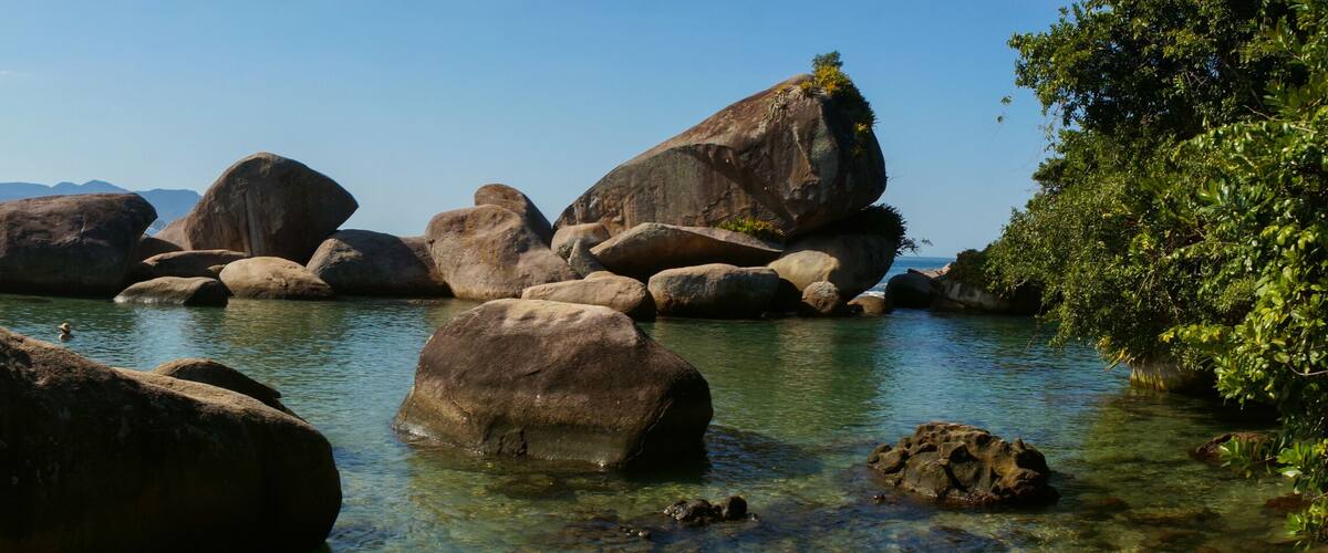 Un río con grandes rocas y agua cristalina, rodeado de montañas.