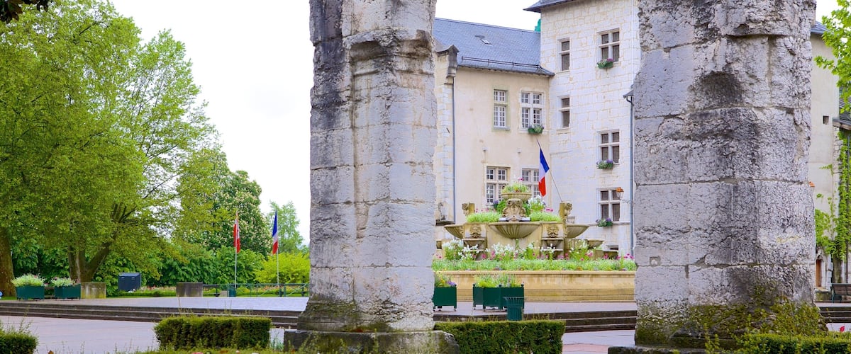 A historic building with a fountain, surrounded by a garden with red and white flowers.