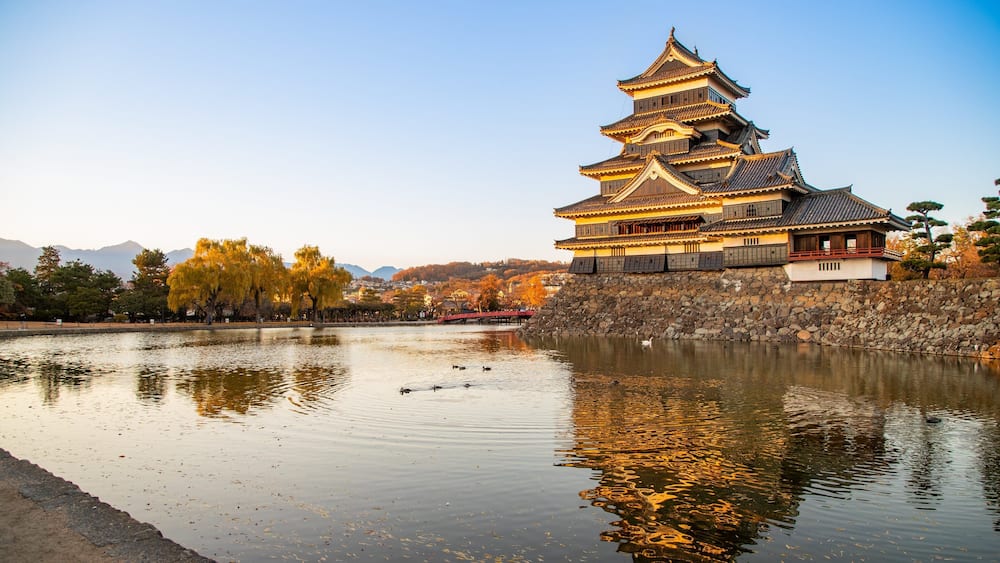 Matsumoto Castle featuring a pond, heritage architecture and a sunset