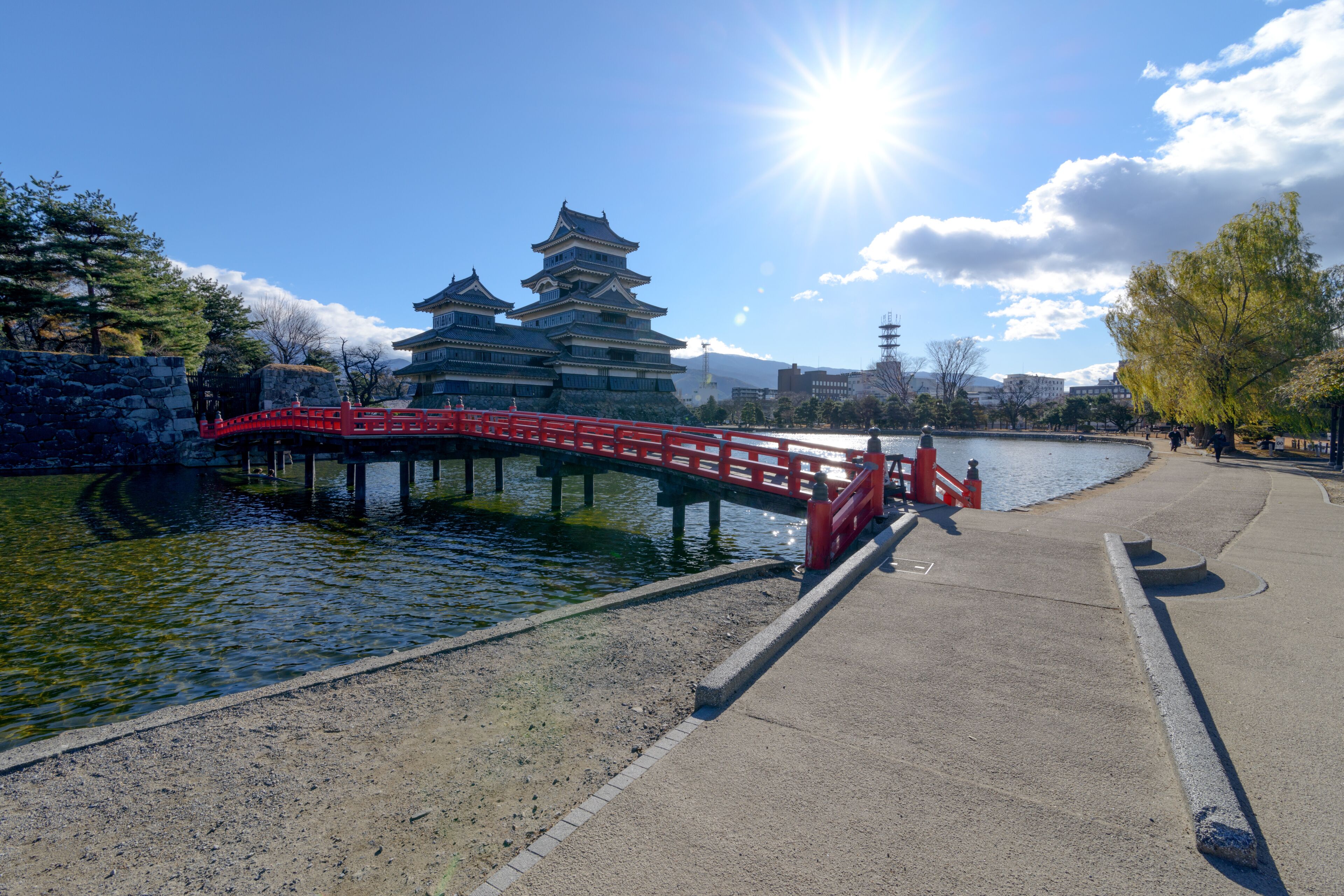 The scenery of the Matsumoto castle on a beautiful clear sky with the red bridge in Nagano, Japan..