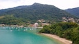 A coastal town with boats on turquoise waters, surrounded by lush green hills.