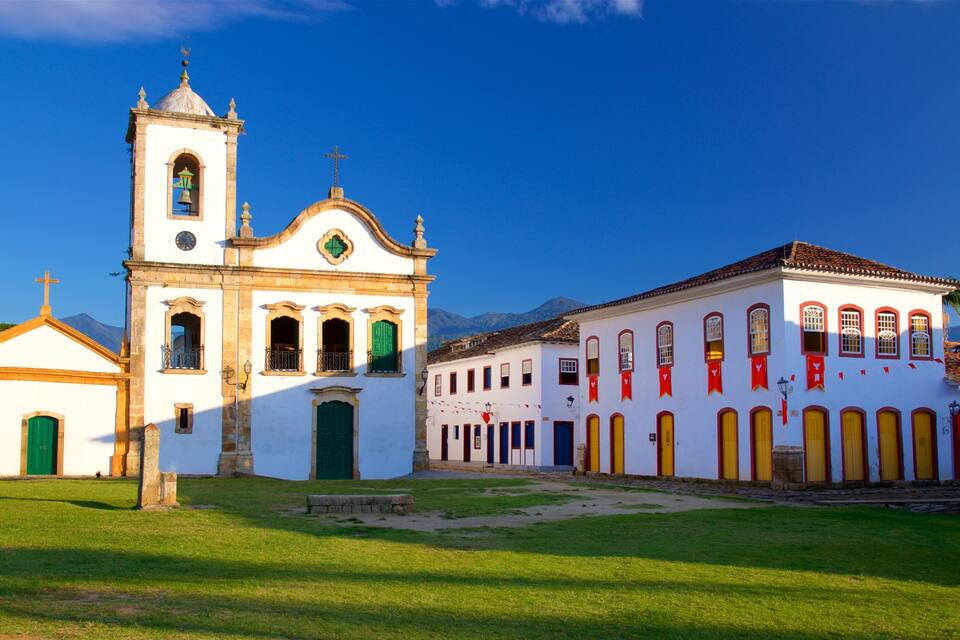A church with a bell tower and a building with colorful flags.