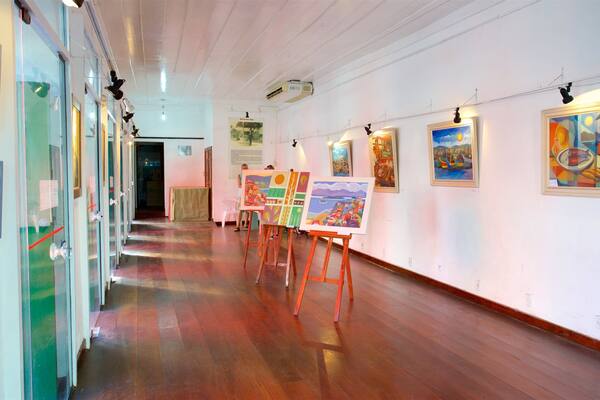 Eine Kunstgalerie mit Holzböden und Gemälden an den Wänden.