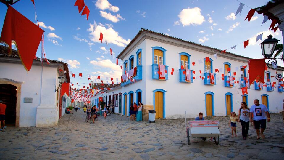 Una calle adoquinada con edificios que tienen puertas y ventanas azules y amarillas, decorados con banderas rojas y blancas.