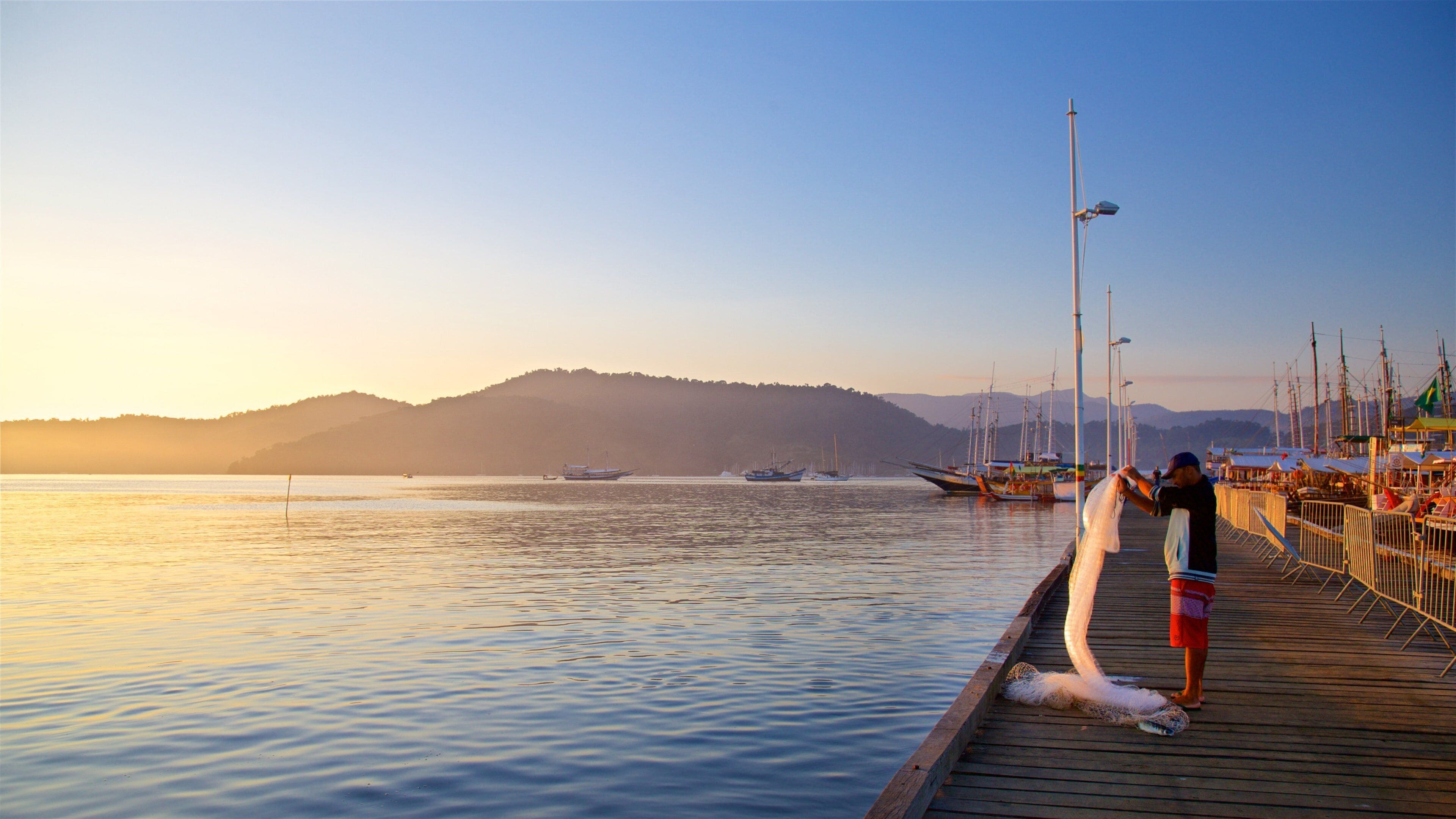 Paraty Wharf featuring a sunset and a bay or harbor as well as an individual male