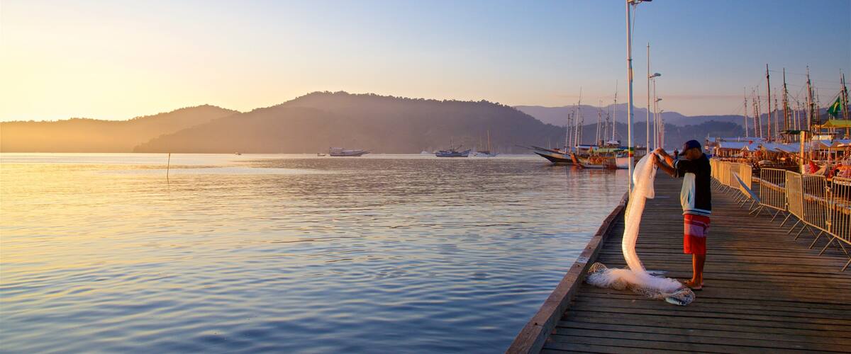 Paraty Wharf featuring a sunset and a bay or harbor as well as an individual male