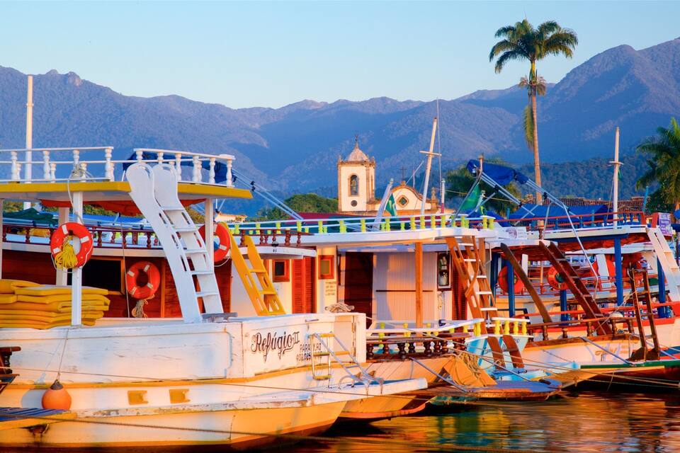 A harbor with boats, a church, and mountains in the background.