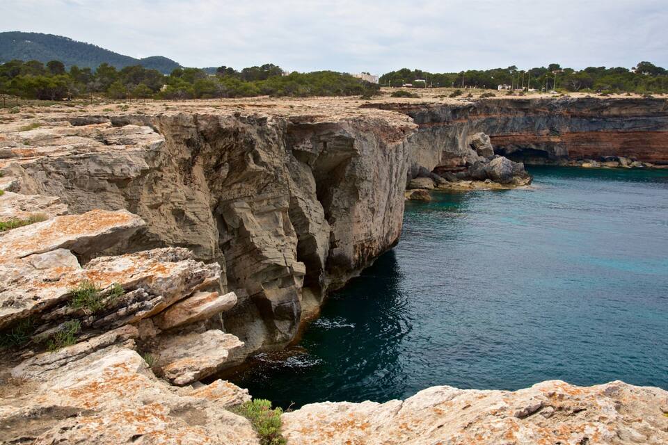 Une falaise rocheuse abrupte, avec une étendue d’eau en contrebas.