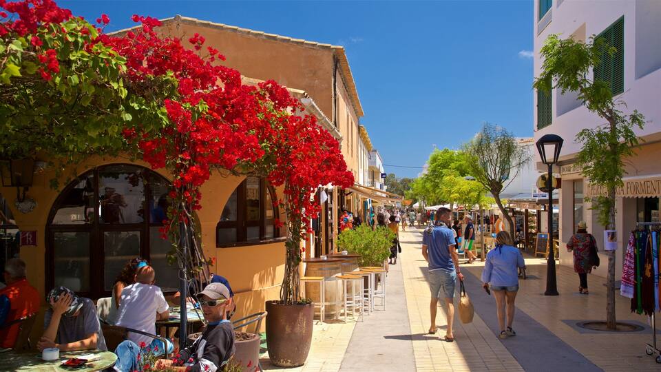A bustling street with red bougainvillea vines, outdoor seating, and people walking.