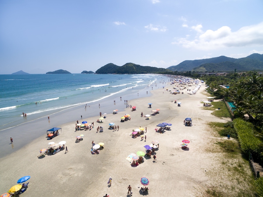 A crowded beach with numerous colorful umbrellas and people enjoying the sunny weather.