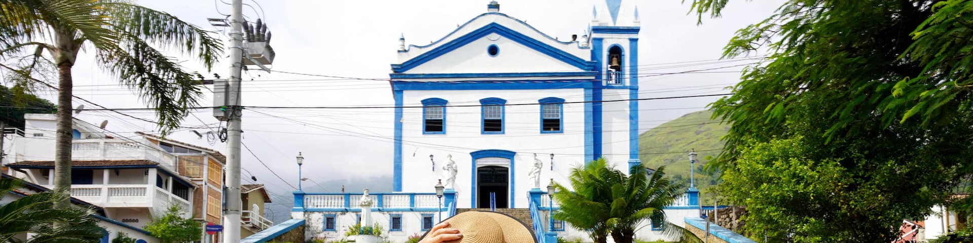 Tourism in Brazil. Back view of tourist girl in front of the church Igreja Matriz in the historic center of Ilhabela Island, Brazil.