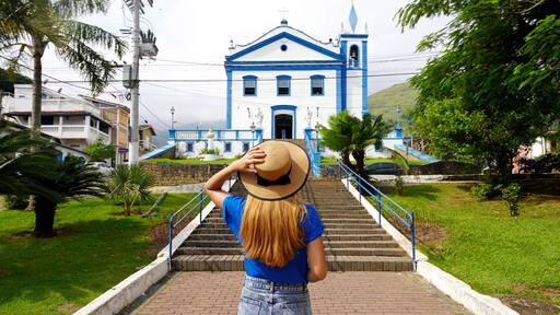Tourism in Brazil. Back view of tourist girl in front of the church Igreja Matriz in the historic center of Ilhabela Island, Brazil.