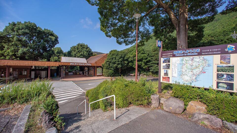 A pedestrian crossing, a signboard with maps and information, and a building with a red roof.