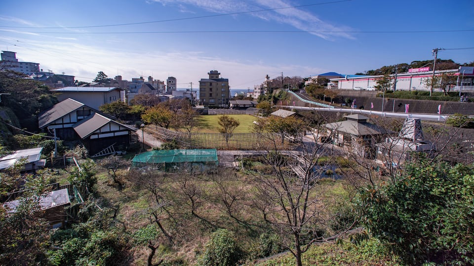 A residential area with houses, a green field, and a distant mountain.