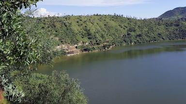 A large lake surrounded by lush green hills and a mountain in the distance.