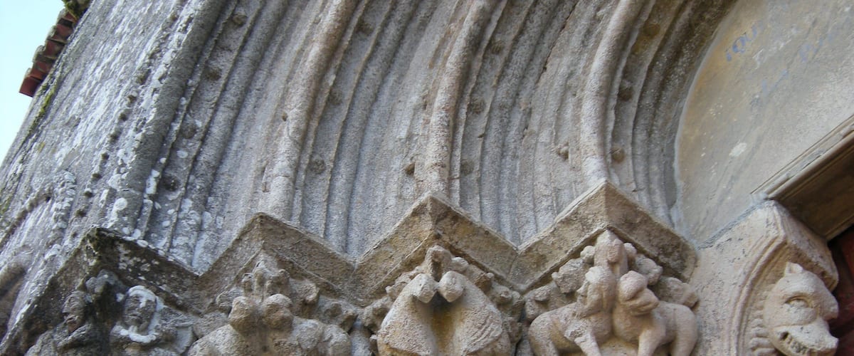 A close-up of a stone column with intricate carvings of human figures and a lion's head.