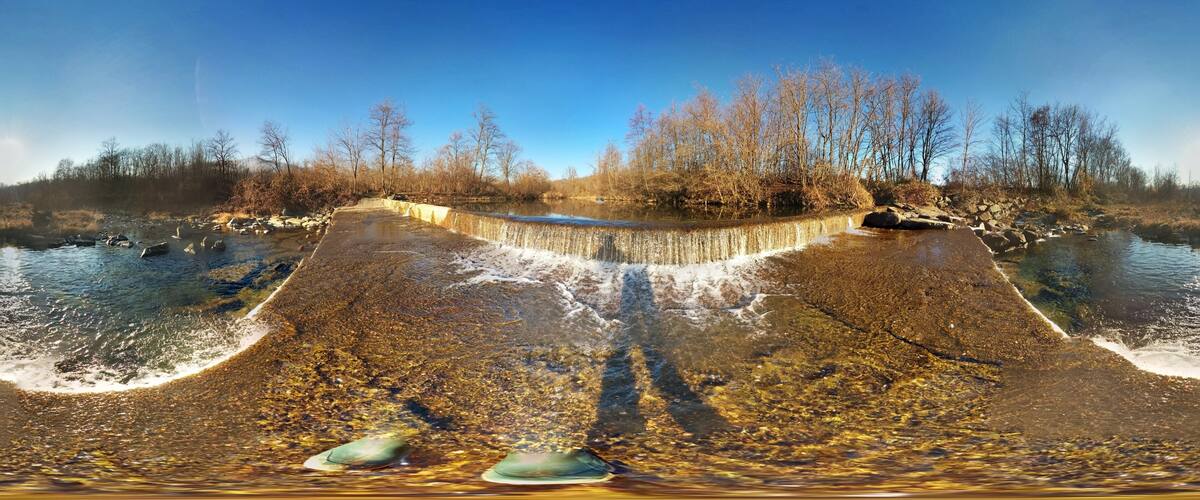 A dam with a clear water spillway and surrounding trees.