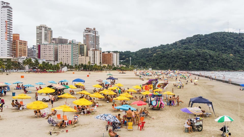 A crowded beach with numerous colorful umbrellas and people enjoying the sand.