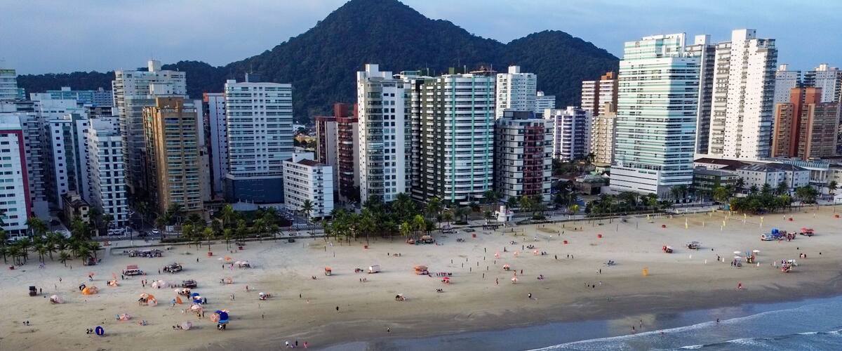 A coastal cityscape with a beach, high-rise buildings, and a mountain in the background.