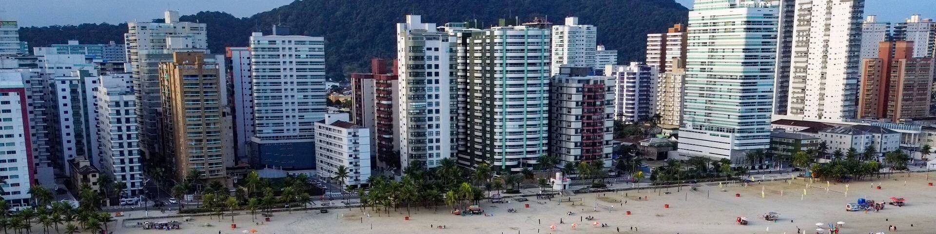 A coastal cityscape with a beach, high-rise buildings, and a mountain in the background.