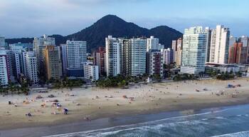Un paisaje urbano costero con una playa, edificios altos y una montaña al fondo.