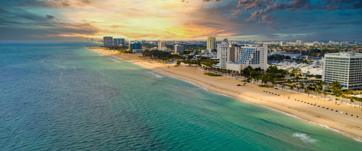 A coastal cityscape with a beach, ocean, and high-rise buildings.