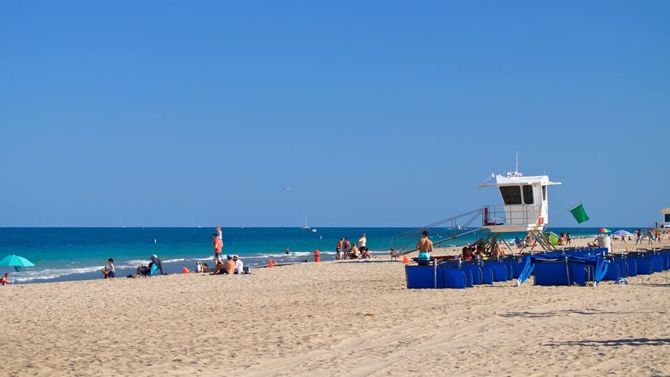 A beach with people, umbrellas, and a lifeguard tower.