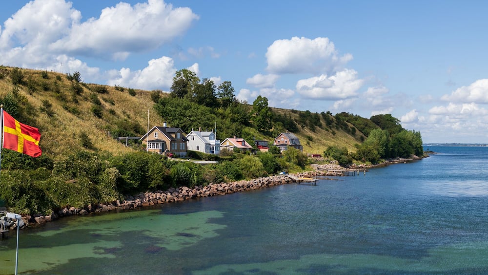 Panorama of the regional flag and part of the island of Ven in southern Sweden taken from the ferry during a warm summer day.