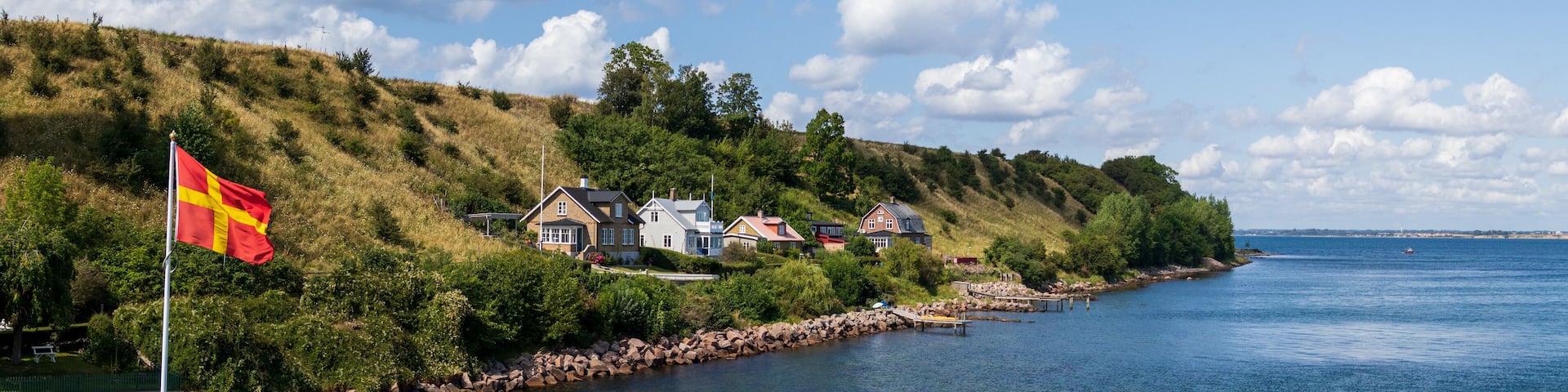 Panorama of the regional flag and part of the island of Ven in southern Sweden taken from the ferry during a warm summer day.