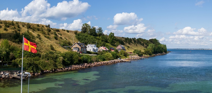 Panorama of the regional flag and part of the island of Ven in southern Sweden taken from the ferry during a warm summer day.