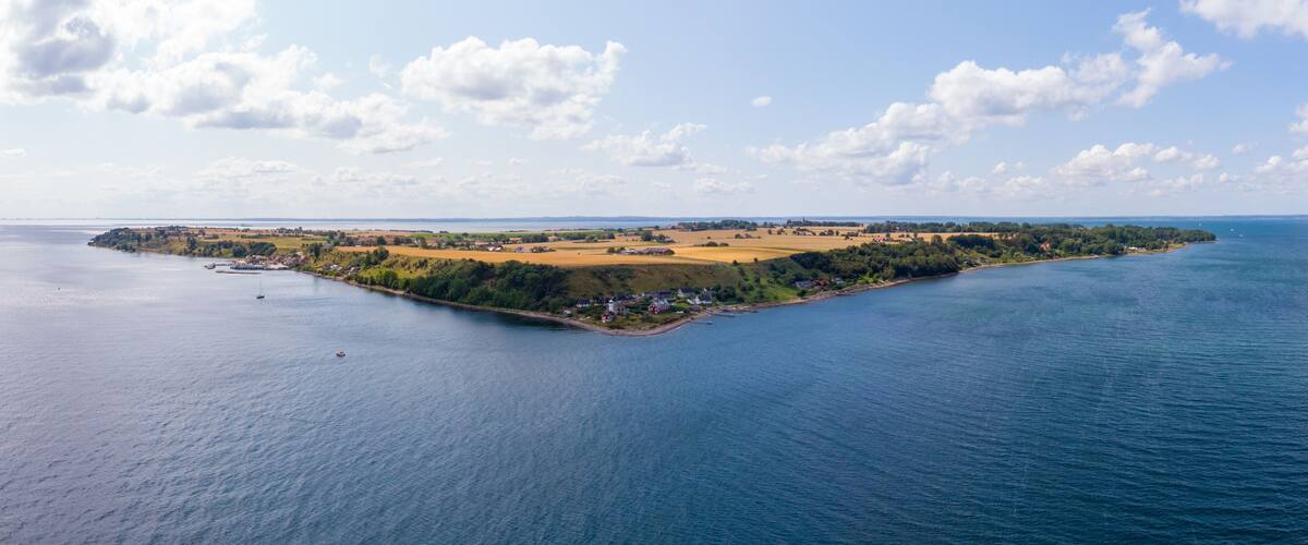 An aerial view of a coastal island with a mix of agricultural fields, residential areas, and a small harbor.