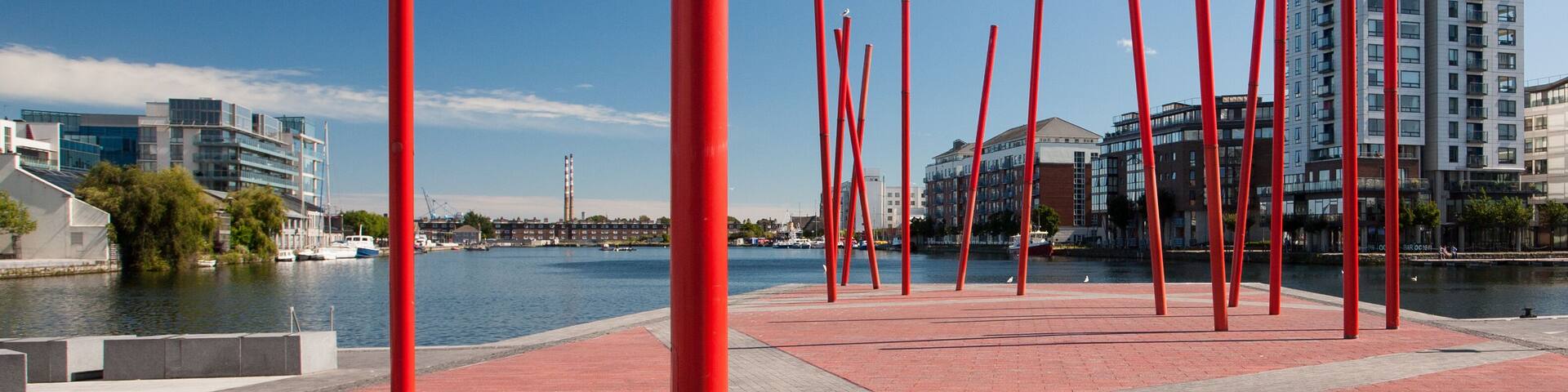 A waterfront promenade with red poles and a river.